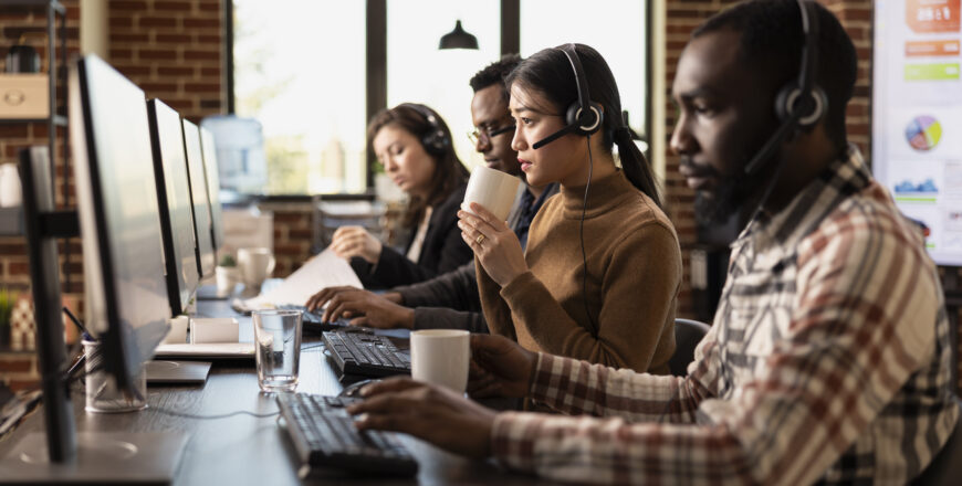 Team of diverse telemarketers sits at their desks