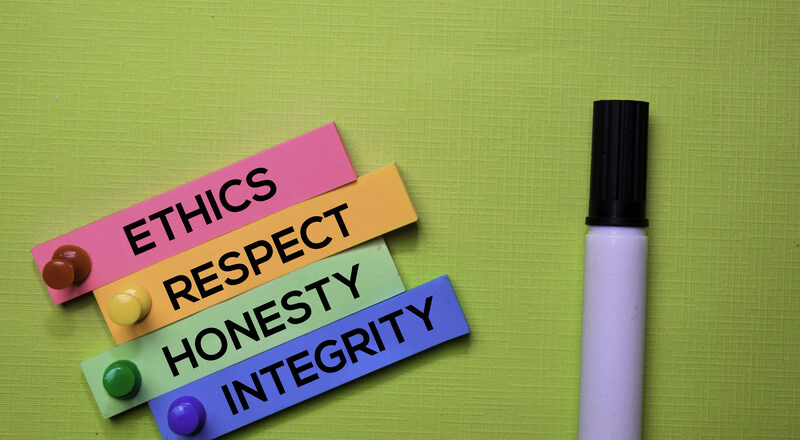 Ethics, Respect, Honesty, Integrity text on sticky notes isolated on green desk.