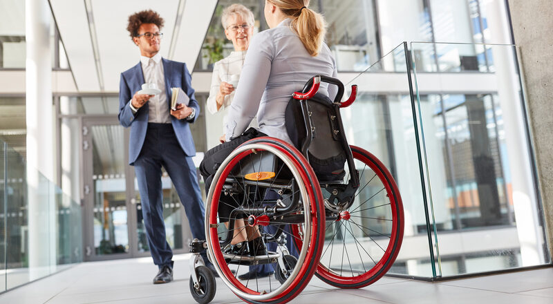 Inclusion and diversity in the business office with a woman in a wheelchair in the company