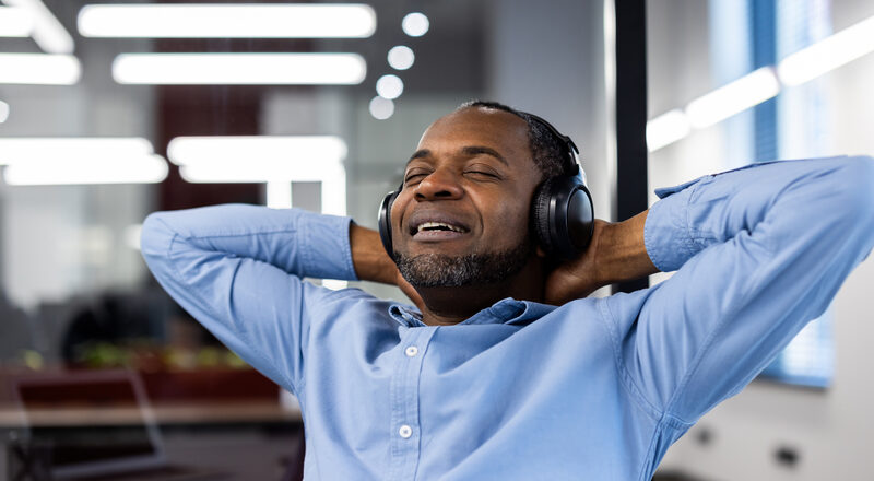 Mature African American businessman relaxing with headphones in office